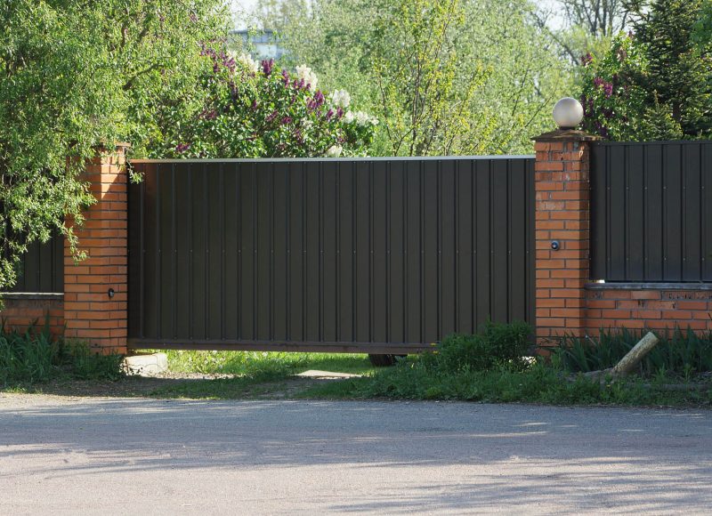 one brown gate and part of the fence of bricks and metal in the