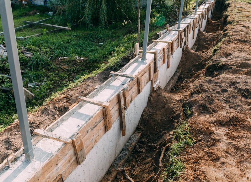 Timber formwork with metal reinforcement with pour concrete and creating a solid foundation for a building or fence. Construction process. Building the retaining wall. Side view. Nobody. Copy space