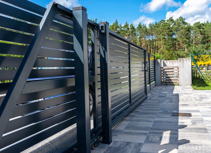 Modern panel fencing in anthracite color, visible sliding gate to the garage as well as a handle and a lock.