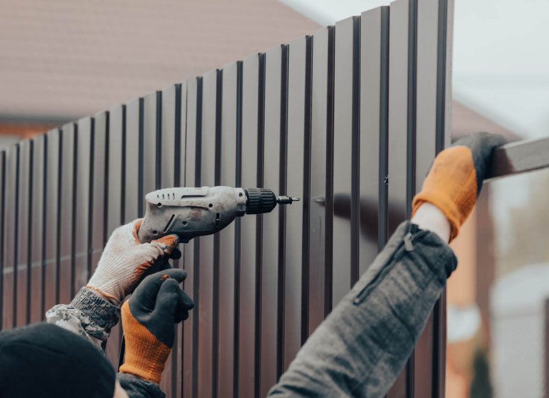 Workers install a metal profile fence