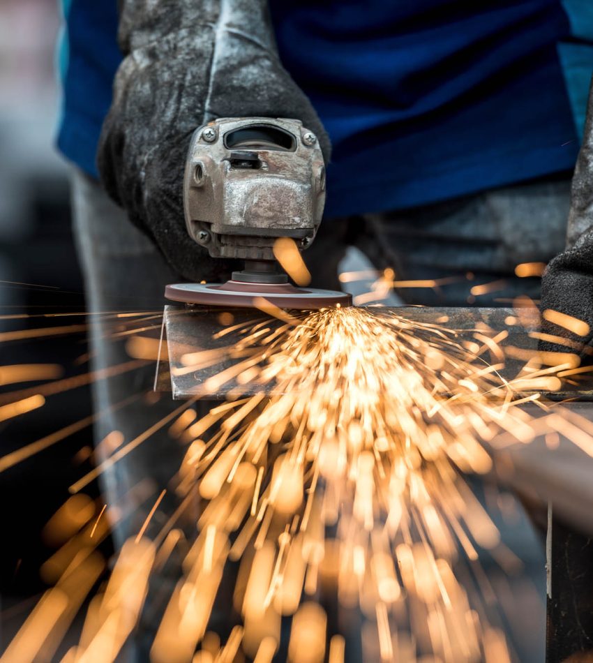Industrial worker cutting metal with many sharp sparks