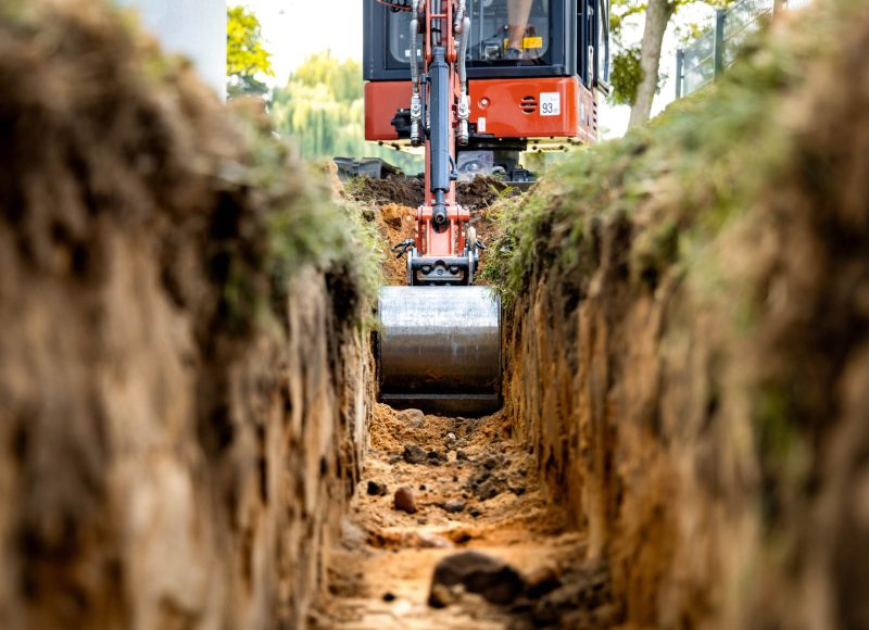 Mini excavator bucket in a trench at a construction site