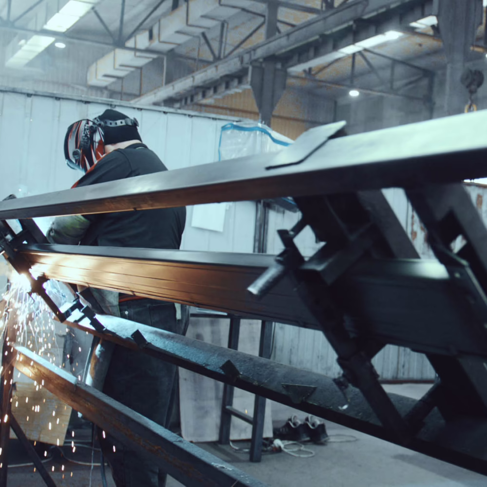 Welder joining metal pieces in factory workshop